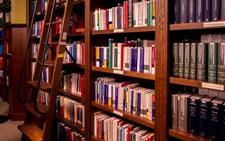 Biblioteca jurídica con estanterías de libros y escalera