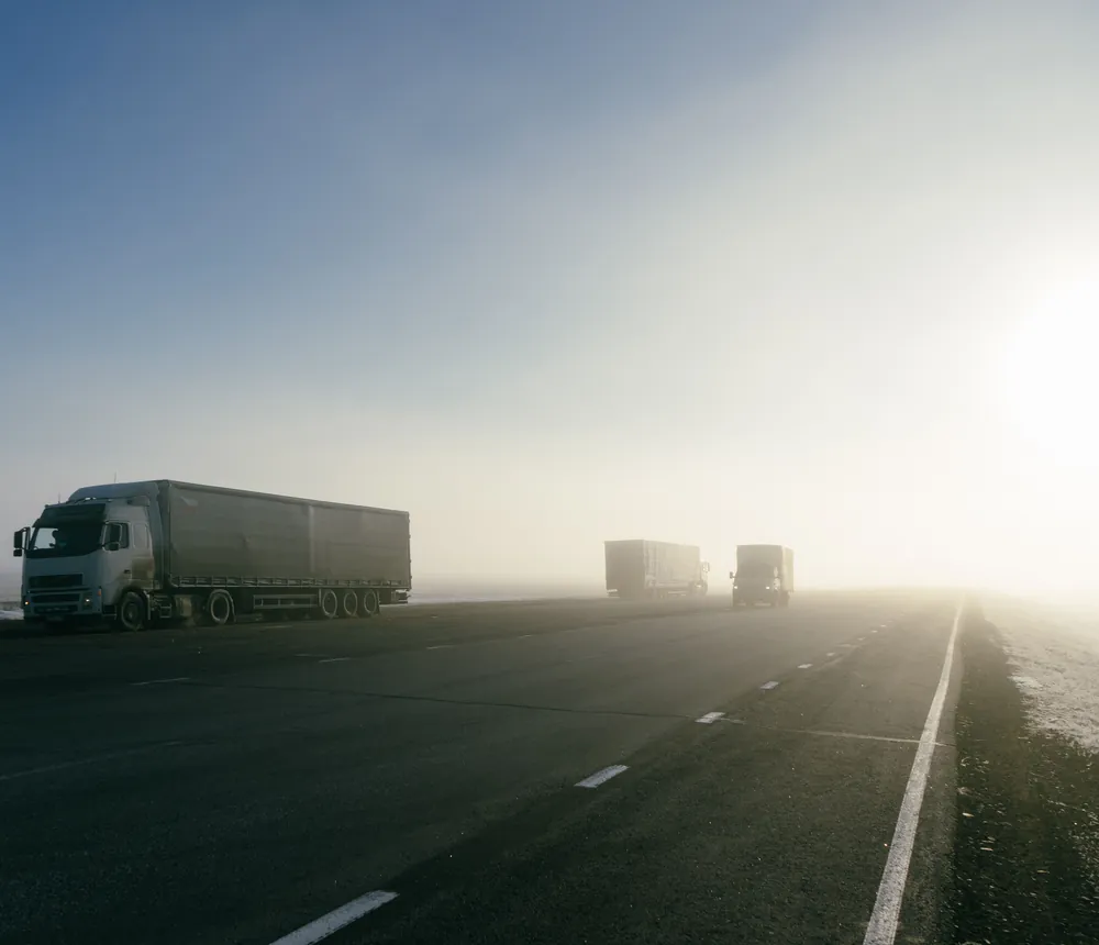 Camiones de transporte de mercancías circulando por una autovía al amanecer