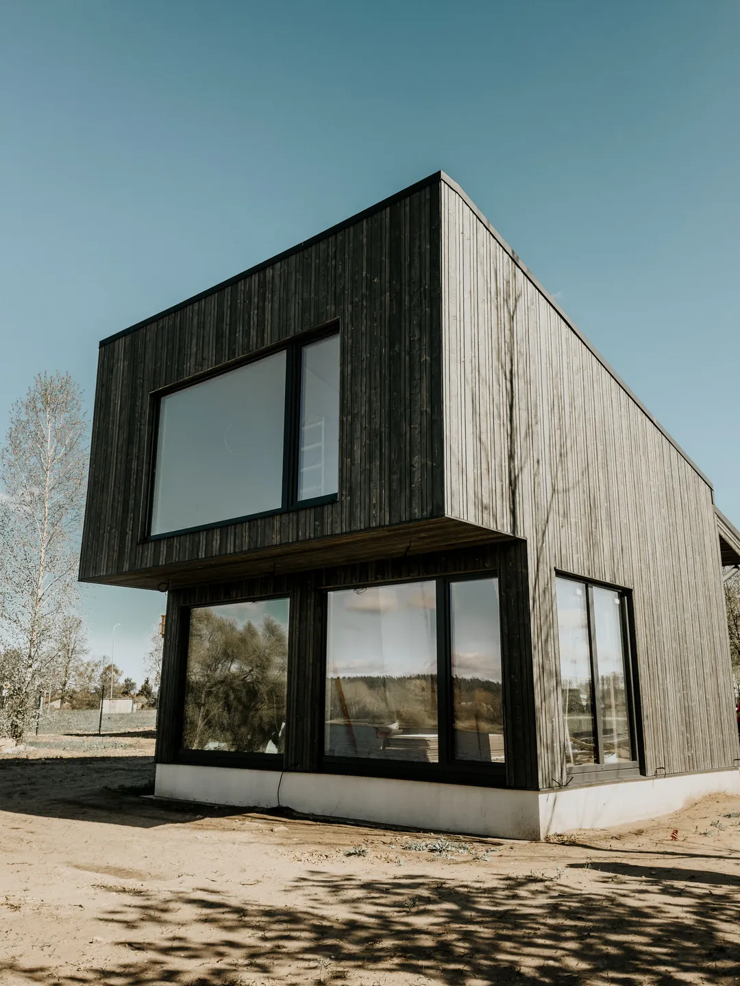 Casa unifamiliar de volumen compacto con fachada de madera oscura y grandes ventanales, típica de la construcción de muy bajo consumo