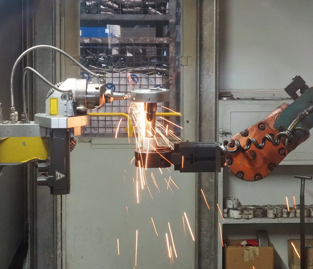 Robot industrial de soldadura trabajando sobre una pieza de acero dentro de una célula robotizada